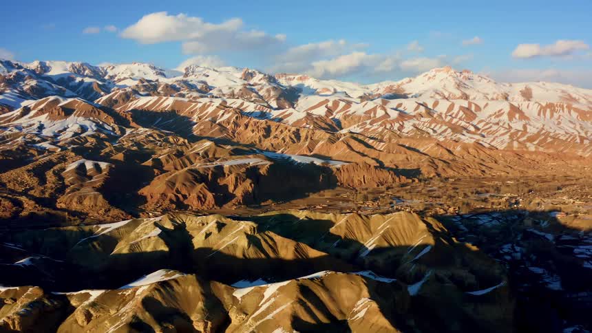 Aerial view of a rural town in a desert valley nested on the snow covered peaks of a mountain range