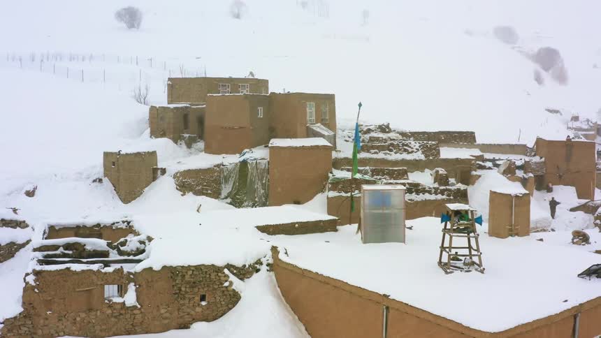 It is snowing on the small stone buildings