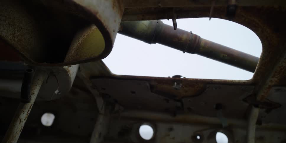 Interior of an abandoned run down rusted military tank under a blue sky