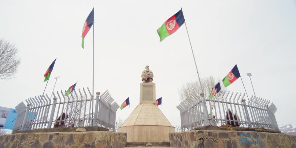 A statue surrounded by a fence and flags