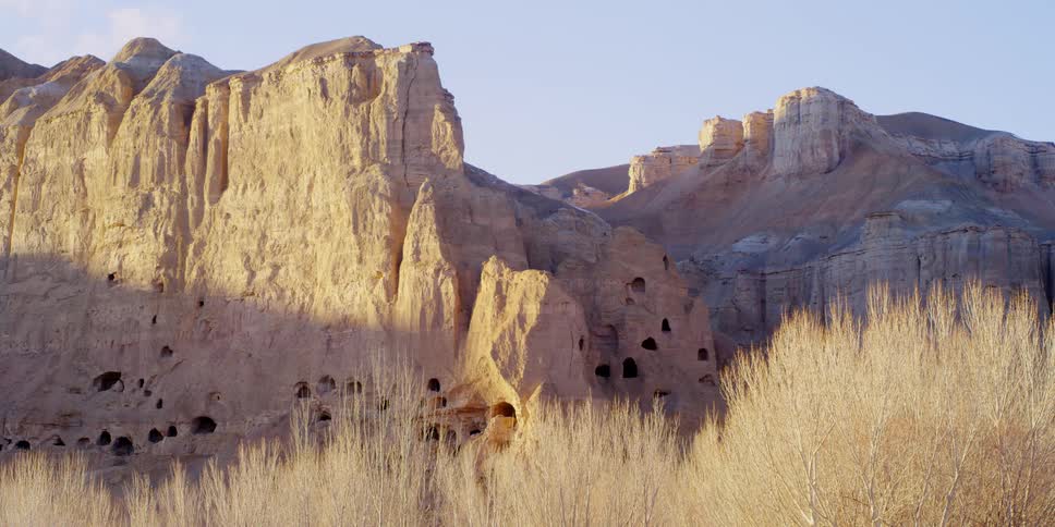 Caves dot the sides of a large mountain cliff
