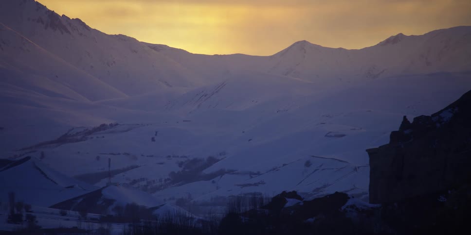A snow covered mountain with buildings at the bottom