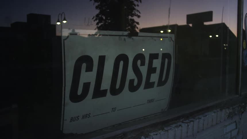 A closed sign hanging in the window of a store