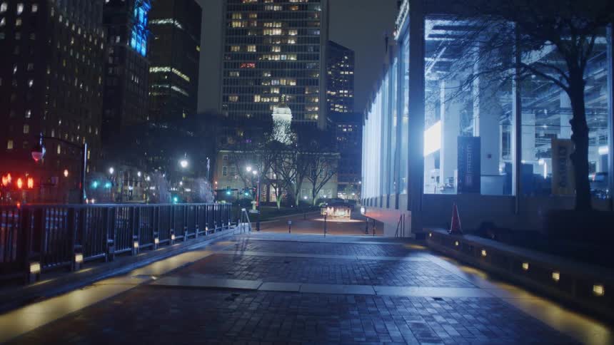 An illuminated walkway near a plaza in a metropolis at night