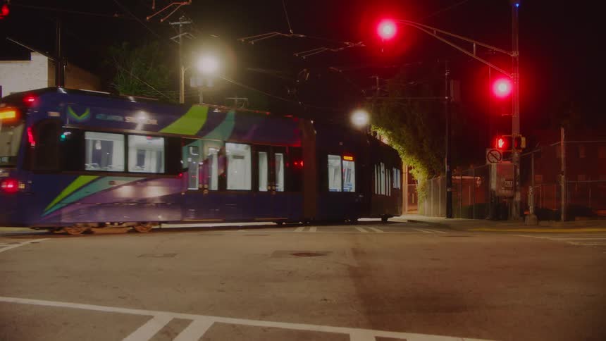 A light rail taking a turn at a city intersection at night