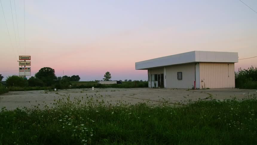 A building on a concrete slab with a sign trees and the sky in the background