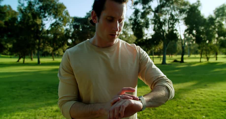 A man is standing outdoors and checking his watch