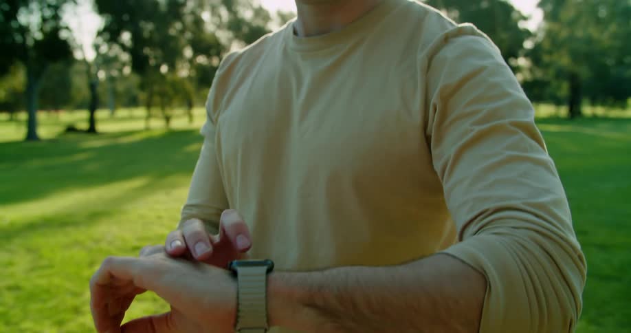 A man is standing outdoors and looking at his watch