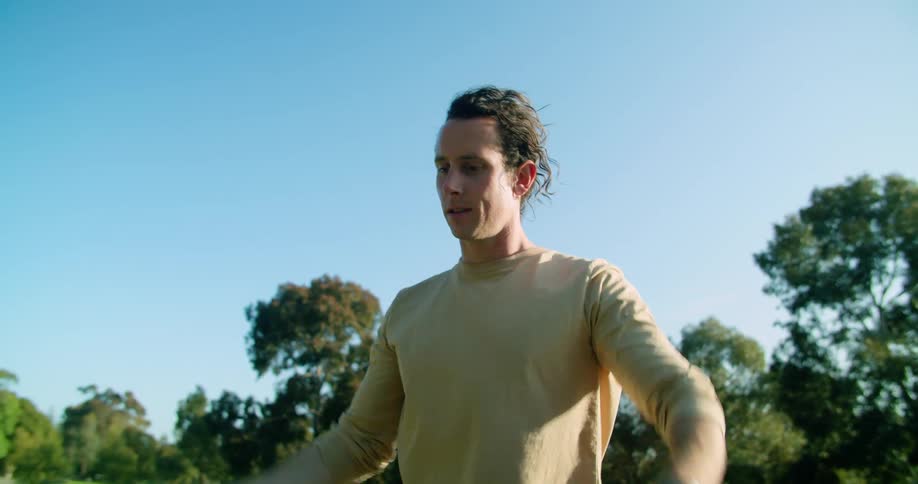 A white man stretches his arms in a park