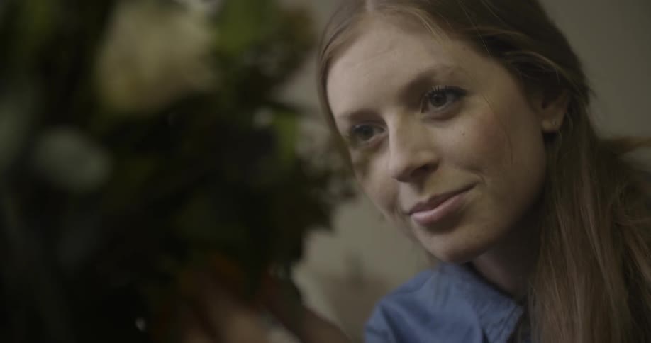 Woman looking at a flower arrangement and smiling
