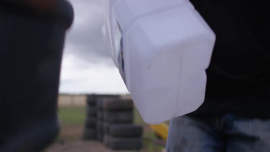 Person lifts large plastic container onto back of vehicle
