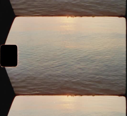 A body of water with ripples with the sun sky and clouds in the background 8mm