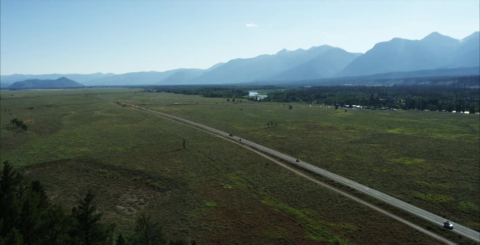 Cars driving next a field in a rural area