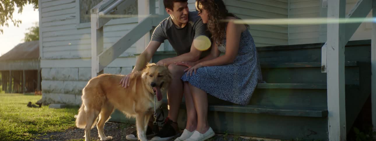 Couple sitting on porch steps talking and petting their dog