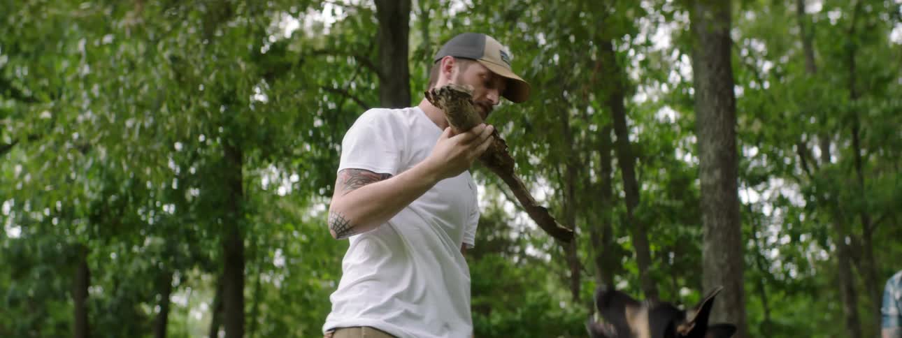 Man plays with dog with branch while another man watches