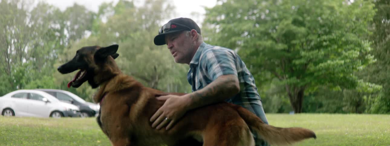 A man is petting his dog outdoors in spring