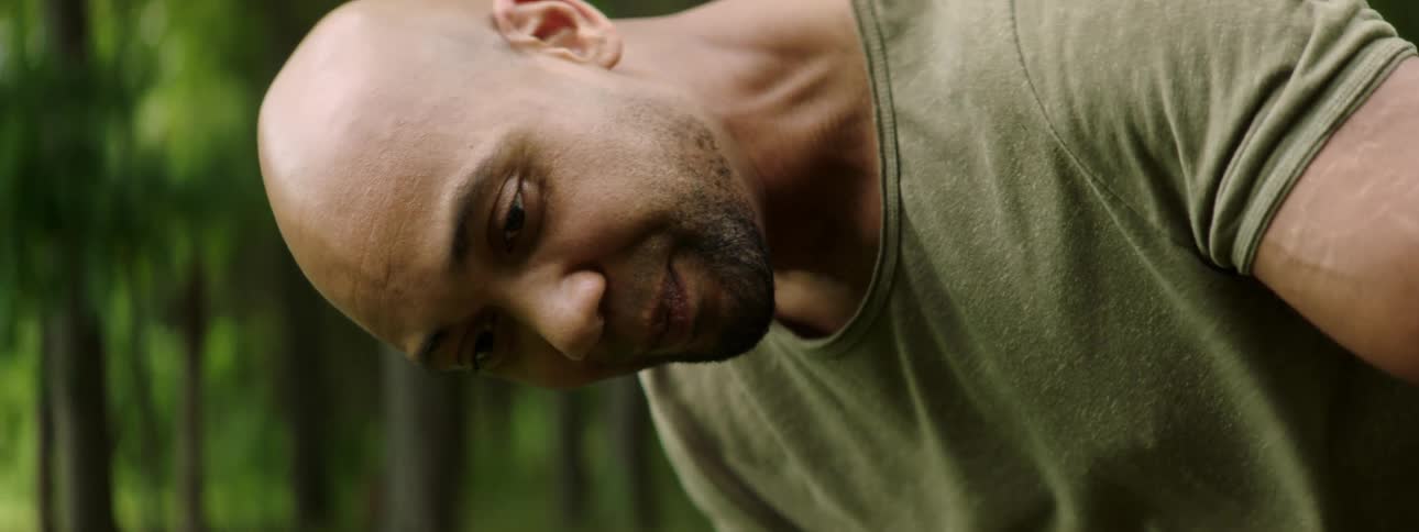 A man in a forest bending down and talking