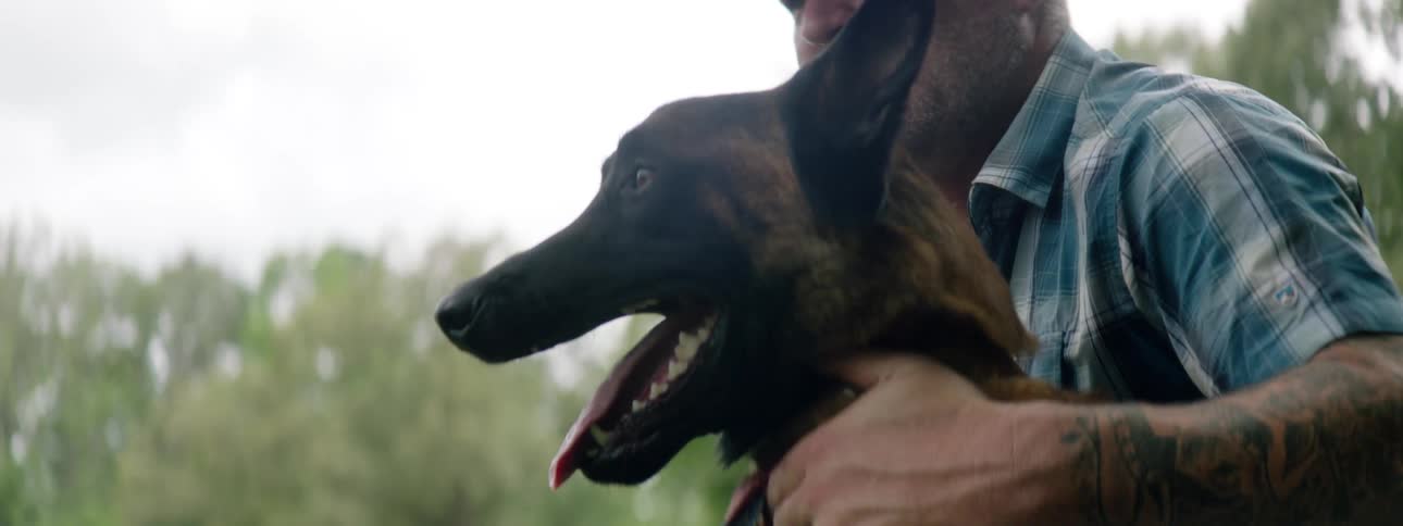 Man sitting outside with his belgian malinois dog