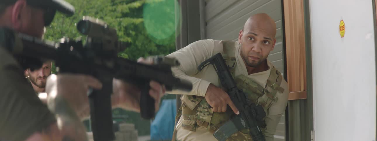 A soldier holding a gun bangs on a door and opens it and then another soldier lets a dog in