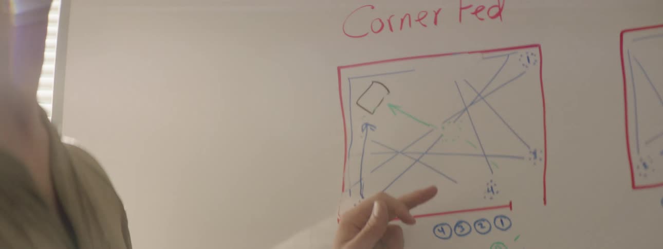 A man gestures at and explains a diagram on a whiteboard