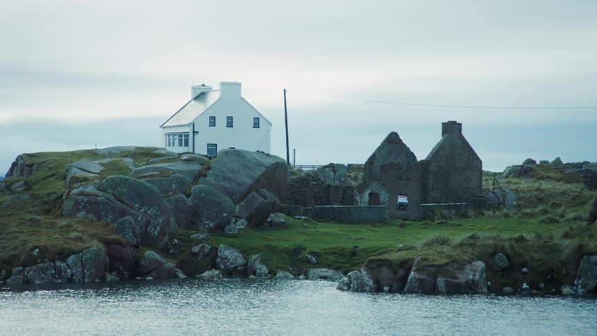 House and ruins of old house on rocky coastline
