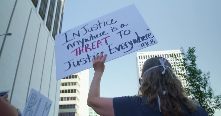 People walk through city skyscrapers carrying protest signs