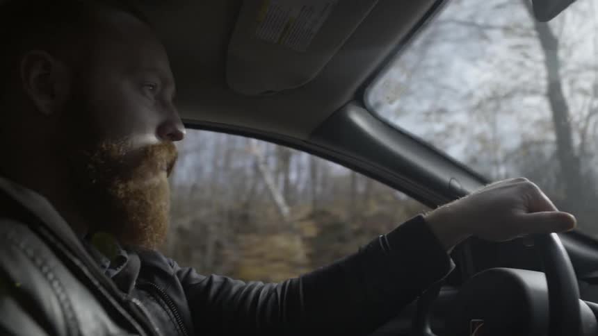 A bearded man drives his car
