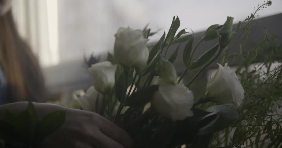 A woman inspecting white roses