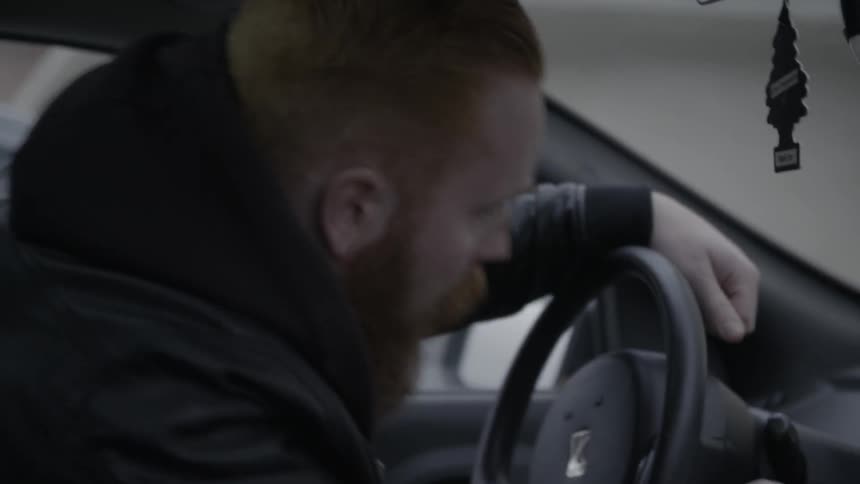 A bearded man climbs into his car