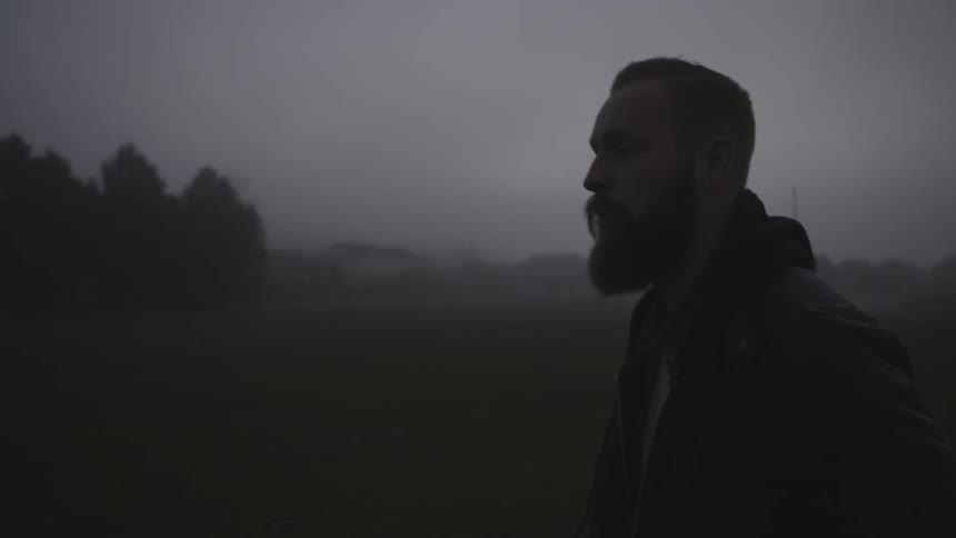 A man walking in an open field on a misty morning