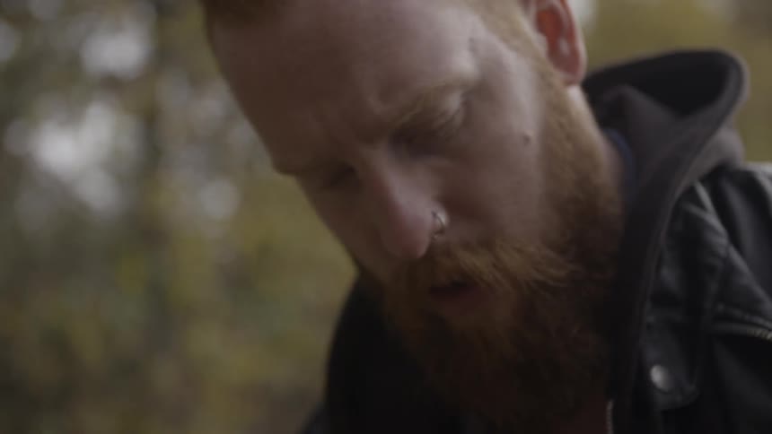 A man is looking down near some trees