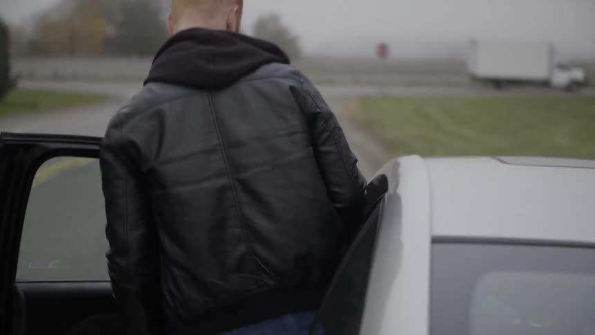 A man gets into his car on the side of the road