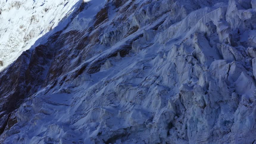 An enormous rocky mountain range is nearly completely covered in snow