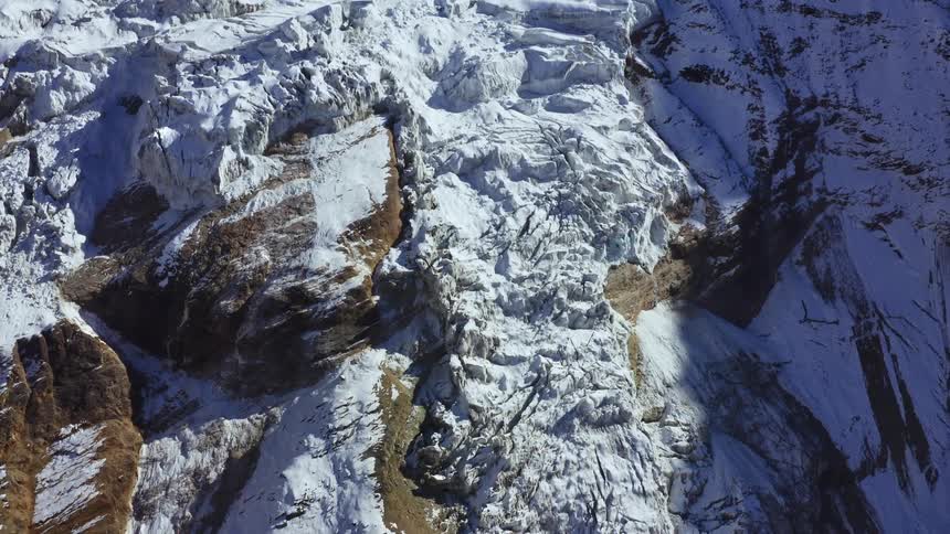 Snow covered mountains slope sits partially in shadow