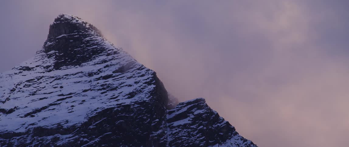 The sun is setting above the snowy mountain