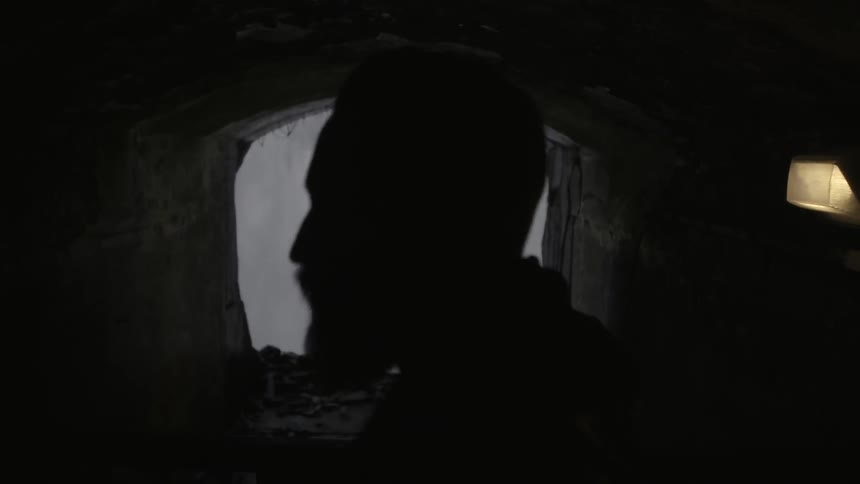Man looking out at a waterfall through an opening in a concrete wall