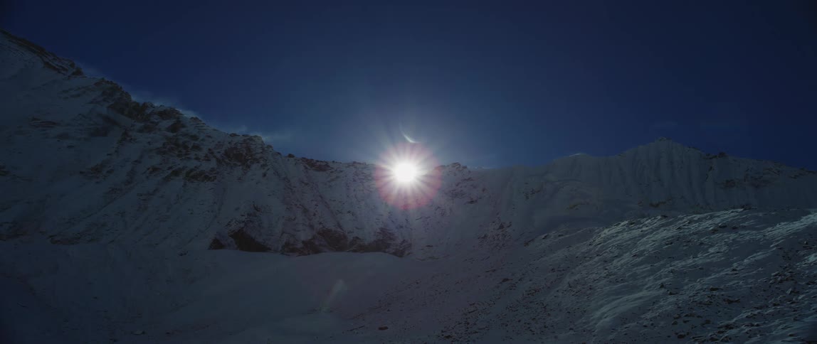 The sun is setting above the mountains in winter