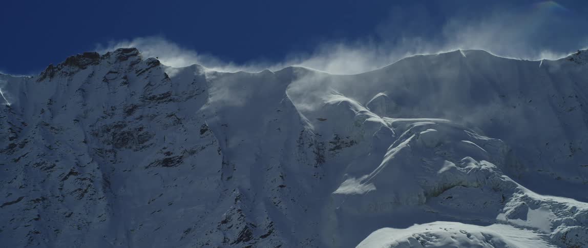 A snow and ice covered mountain range with the sky in the background