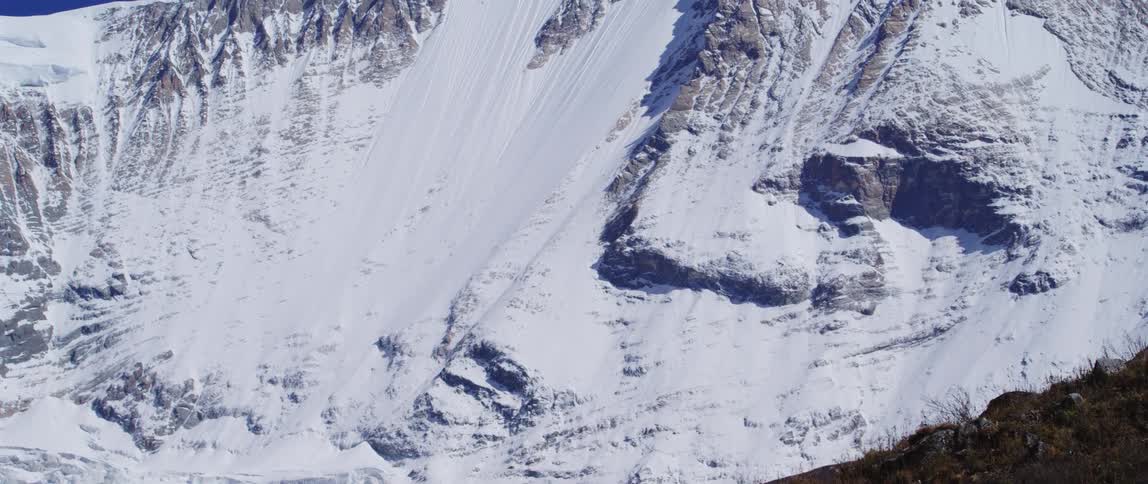 Skiers standing on a ridge looking at a snowy mountain in winter