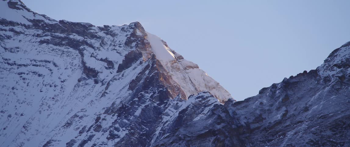 Snowy mountains are displayed at dusk