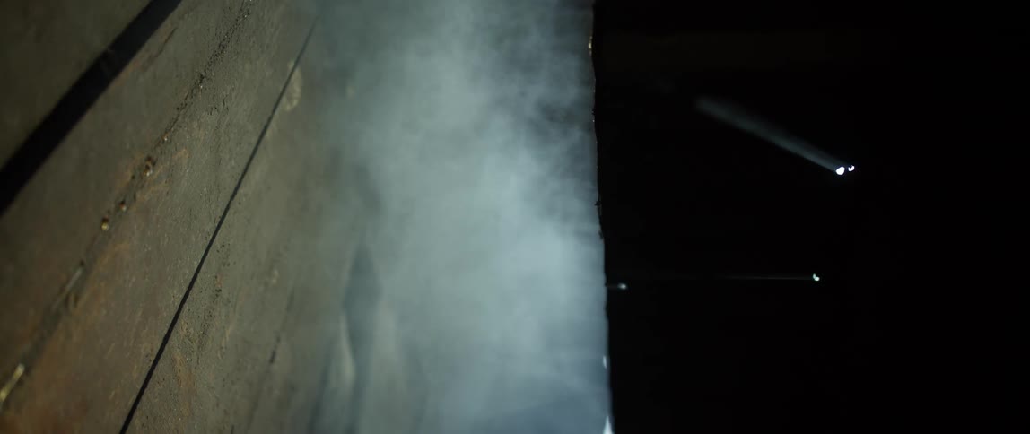 Smoke or steam billows as light glows above wooden boards