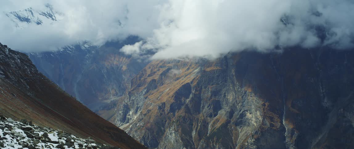 Clouds move across the summit of a mountain range during the day