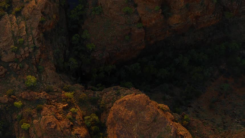 Bushes cover red dirt valley between mesa