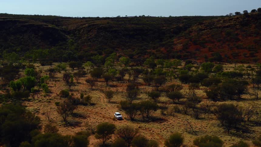 An aerial view of a car driving across a grassland