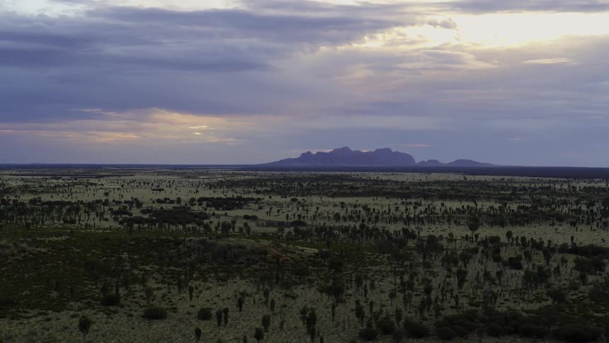 Grassland in front of distant mountains at dusk