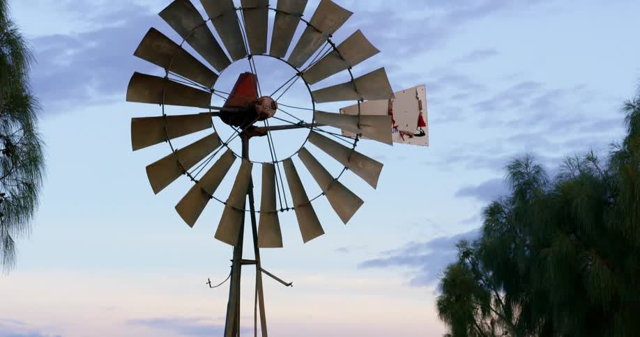 Metal farm windmill at sunset
