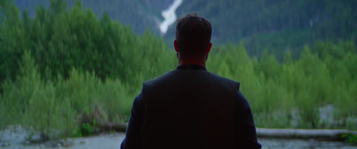 A man is walking through a forest at midday