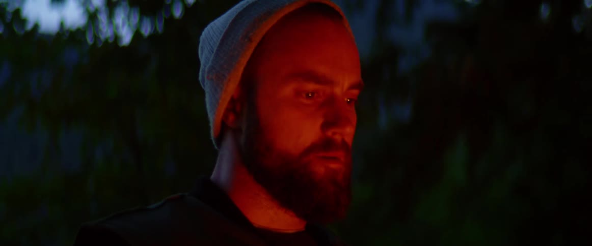 Man standing by campfire in late evening