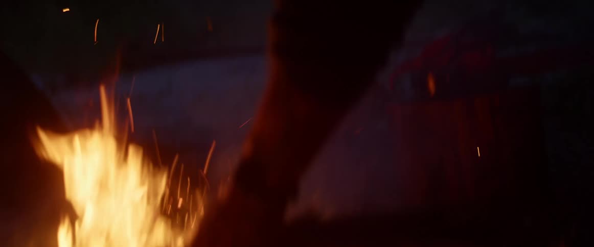 Man adds wood to bonfire at night
