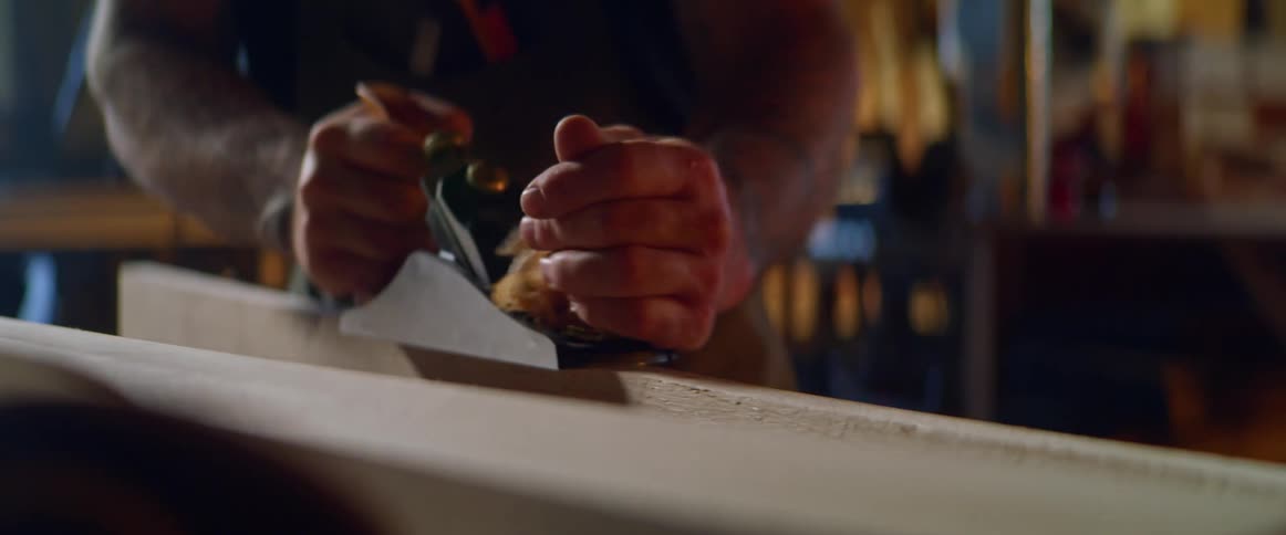 A man is shaving wood in a shop